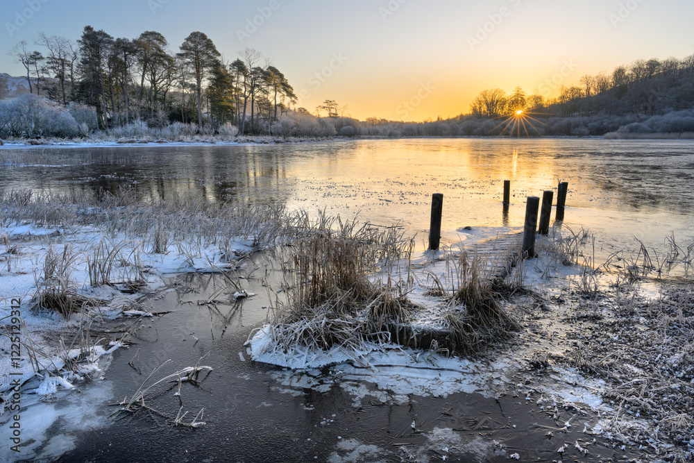 Φωτογραφία Flooded wooden jetty leading out over small frozen lake on a crisp winter morning