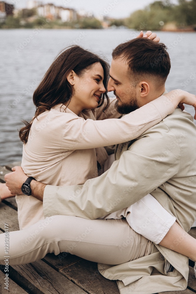 Obraz premium strong embrace of a man and a woman in love posing for a photo in front of a city lake in the cool season, having fun together, selective focus, noise effect