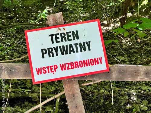 A sign with the inscription Teren prywatny, No entry, Private Property in Polish, with restrictive tape and trees in the background. Perfect for themes of property, privacy, and boundaries. photo