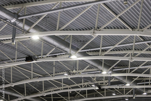 Ice hockey rink roof view with white ceilling lines, pipeline, LED ligting and music speakers hanging.