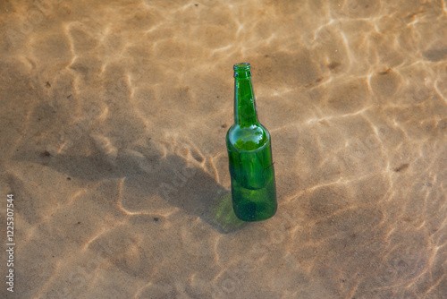 Green glass bottle floating in a river, bottleneck seen over water surface. photo