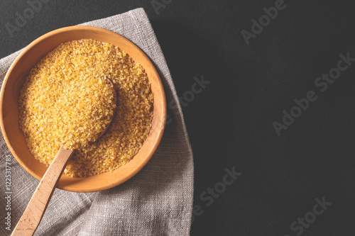 Wheat bulgur in a wooden plate on the table. Top view