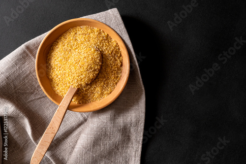 Wheat bulgur in a wooden plate on the table. Top view