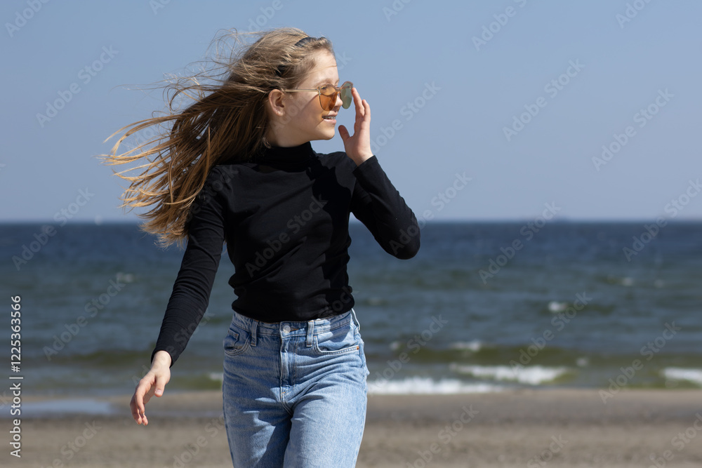 Playful teenage girl in sunglasses having fun on the beach.