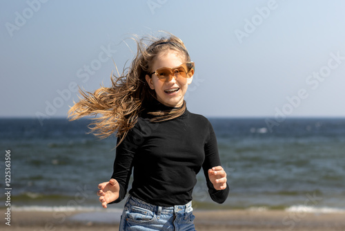 Playful teenage girl in sunglasses having fun on the beach.