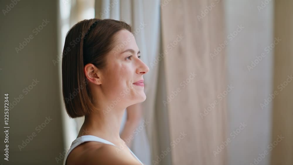 Smiling woman pulling curtains enjoying morning routine closeup. Reflective lady