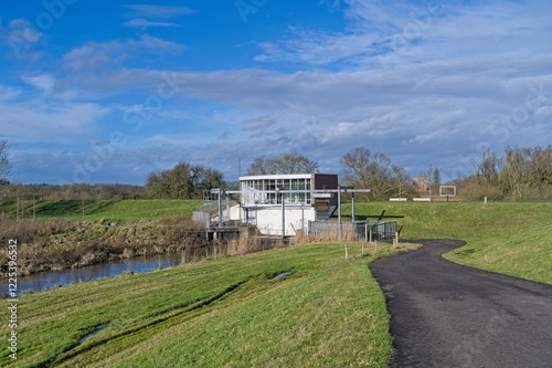Gemaal Middelbeek on the dike on the river IJssel with castle ruins Nijenbeek in the background. photo