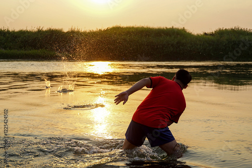 Asian men play Stone skipping by throwing stones that bounce on the surface of the water, creating ripples on the water surface around the stones that gradually widen into ripples.