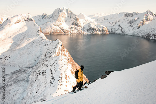 Splitboarder standing on his splitboard in the foreground and admiring the beauty of mountain range photo