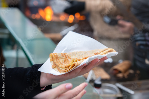 Enjoying a freshly made crepe at a bustling street market in winter