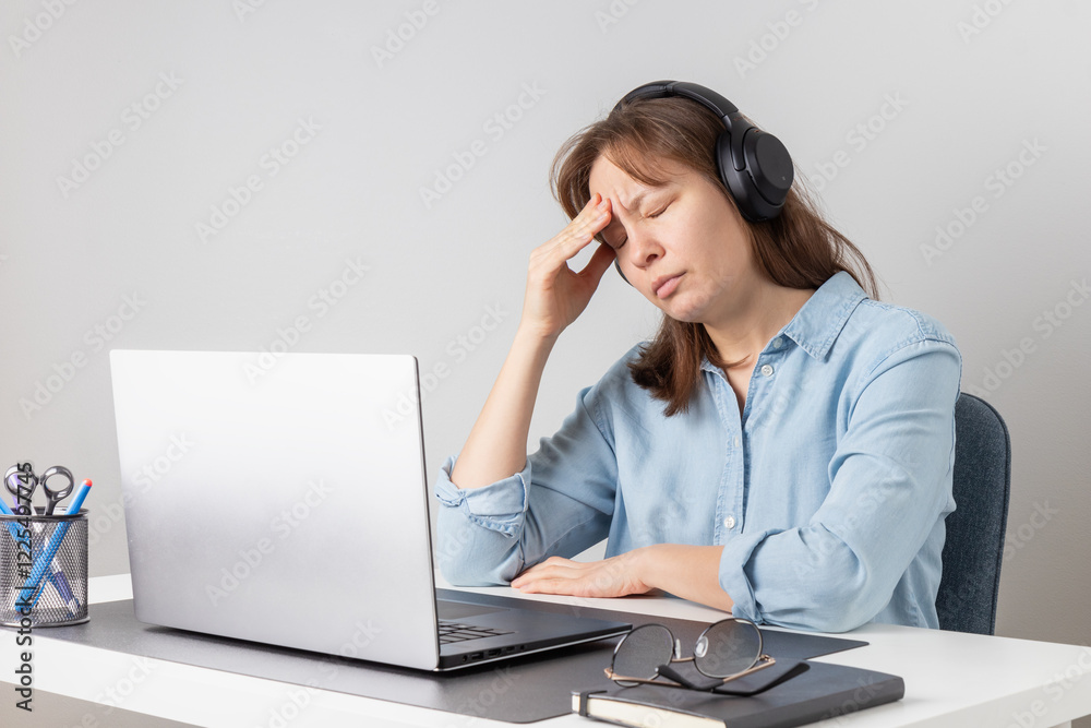 An overworked female freelancer is tired and stressed behind her laptop. Exhaustion and burnout problem of remote working. Woman struggles with fatigue and job-related stress An overworked female freelancer is tired and stressed behind her laptop. Exhaustion and burnout problem of remote working. Woman struggles with fatigue and job-related stress
