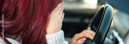 Woman behind the wheel of a car, holding her head: feeling unwell, accident photo