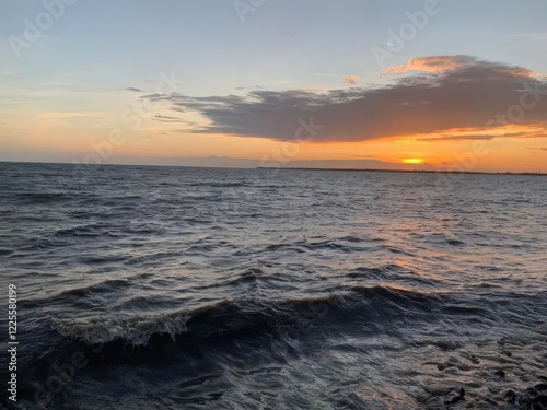 A beautiful sunset paints the ocean horizon with vibrant orange and red hues