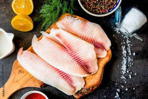 Fresh fish fillet with ingredients for cooking and seasonings on the chopping board