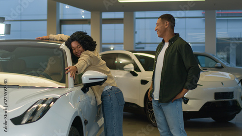 Happy couple african american woman man new car owners choosing automobile at showroom smiling husband wife enjoying purchase in auto dealership boyfriend make surprise for girlfriend buying vehicle