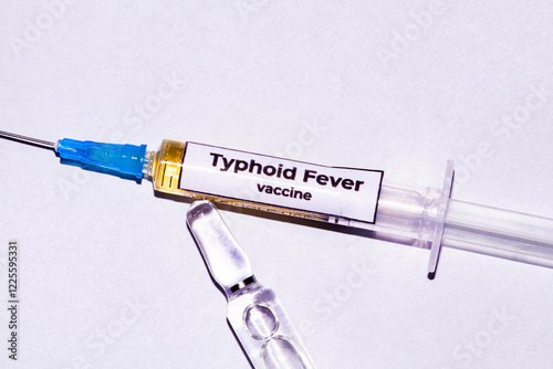 Picture on a white background with a syringe full of typhoid fever virus vaccines, and next to it are some full ampoules that serve as vaccine mixtures. photo