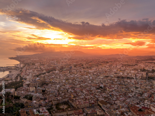 Aerial view of Malaga town center, el ejido, San Felipe Neri, La Goleta Ventaja Alta neighborhoods, Gibralfaro castle dramatic colorful sunset sky