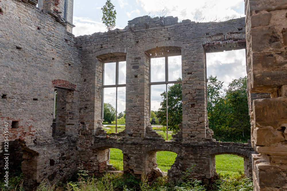 Ruin of Historic Castle in Lush Green Field Under Clouded Sky
