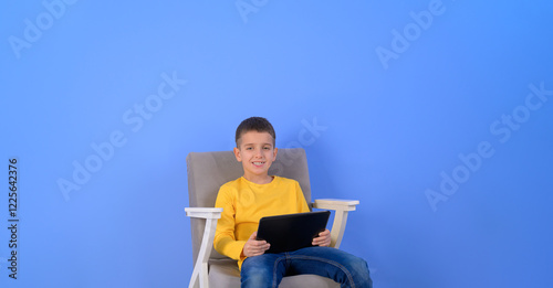 Wallpaper Mural Portrait of smiling cute businessman using digital tablet while sitting on armchair over blue background Torontodigital.ca