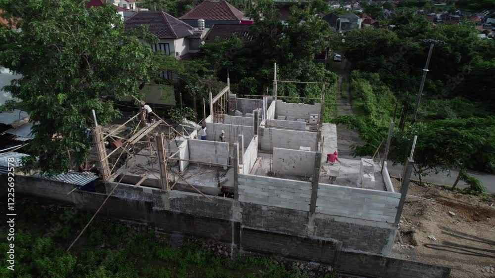 Ariel view on a construction site of house in residential area. Asian construction site in Bali place. Drone view on Villa with builders. House from white brik under construction. Ariel view on a construction site of house in residential area. Asian construction site in Bali place. Drone view on Villa with builders. House from white brik under construction.