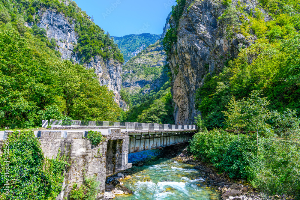 Automobile bridge across the mountain river in Abkhazia against the background of the sky in the valley of the Caucasus Mountains and Rocks. Road to the in Yupsharsky Canyon.Trip, travel on vacation Automobile bridge across the mountain river in Abkhazia against the background of the sky in the valley of the Caucasus Mountains and Rocks. Road to the in Yupsharsky Canyon.Trip, travel on vacation