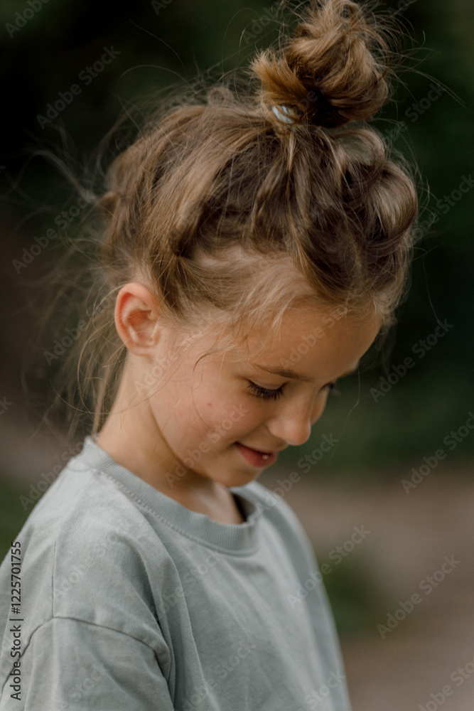 portrait of a cute blond girl with hair twisted into a bun on a blurred green park background portrait of a cute blond girl with hair twisted into a bun on a blurred green park background