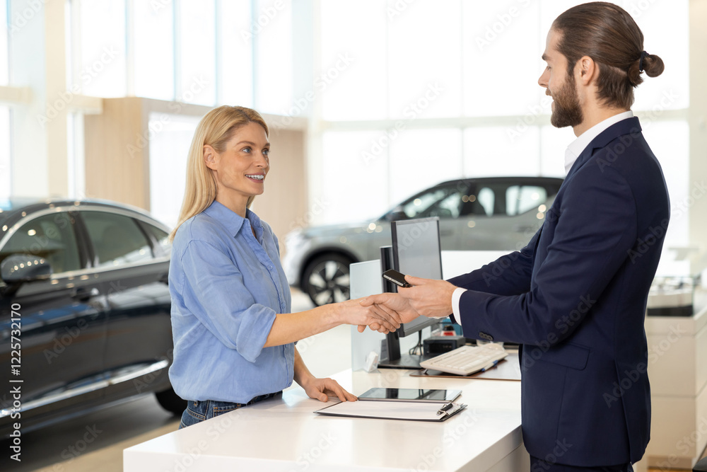 Fototapeta premium Blonde female client buying a new car and paying by card