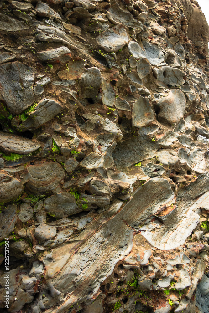 Obraz premium A rock wall with many small rocks and some green moss