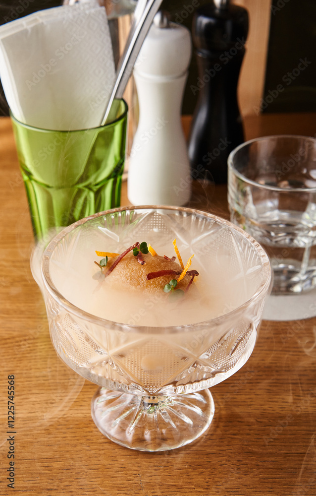 An eye-catching sorbet is served in a crystal glass, garnished with colorful elements. The table features various dining accessories, creating an inviting atmosphere An eye-catching sorbet is served in a crystal glass, garnished with colorful elements. The table features various dining accessories, creating an inviting atmosphere