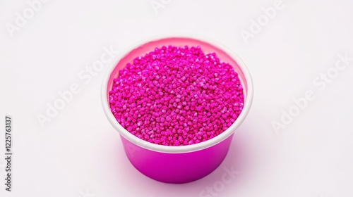 Neon pink masterbatch granules in a cup on a white background Color pigment carrier polymer in the plastic industry photo