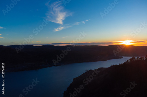 Aerial view of a river between hills seen in the evening at sunset