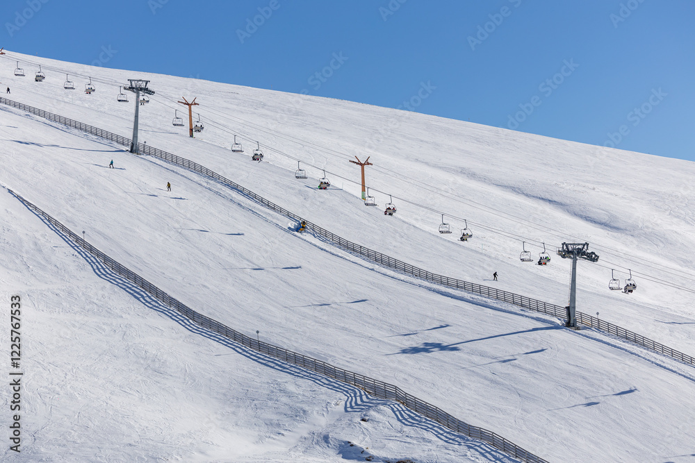 Ski slopes and chairlifts at Cota 2000, Sinaia, Romania, with a snow-covered mountain landscape under a clear blue sky. A perfect winter sports destination. Travel to ski in Romanian mountains.