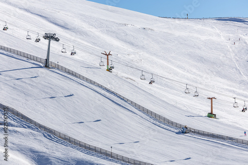 Obraz na płótnie Skiers and snowboarders enjoy the breathtaking view from chairlifts at Cota 2000, Sinaia, Romania, with mountain peaks in the distance under a serene winter sky. Ski in the Romanian mountains. w salonie