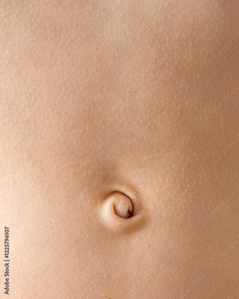 Fototapeta premium Smooth baby belly with a close-up of a curled navel. Soft skin texture and warm tones create a delicate and natural aesthetic.