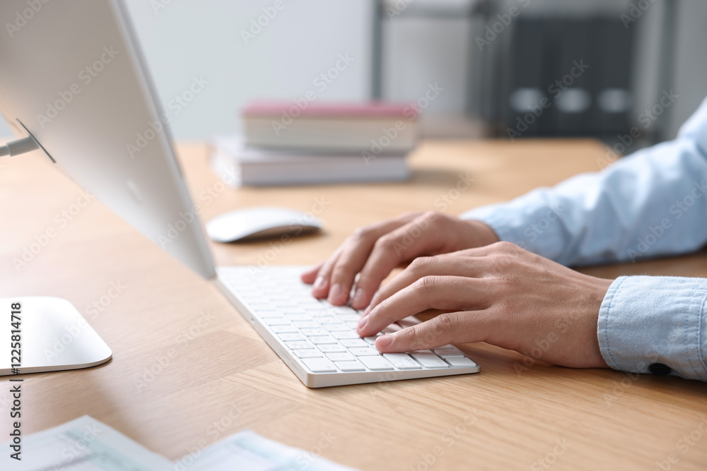 Man working on computer at wooden desk in office, closeup Man working on computer at wooden desk in office, closeup