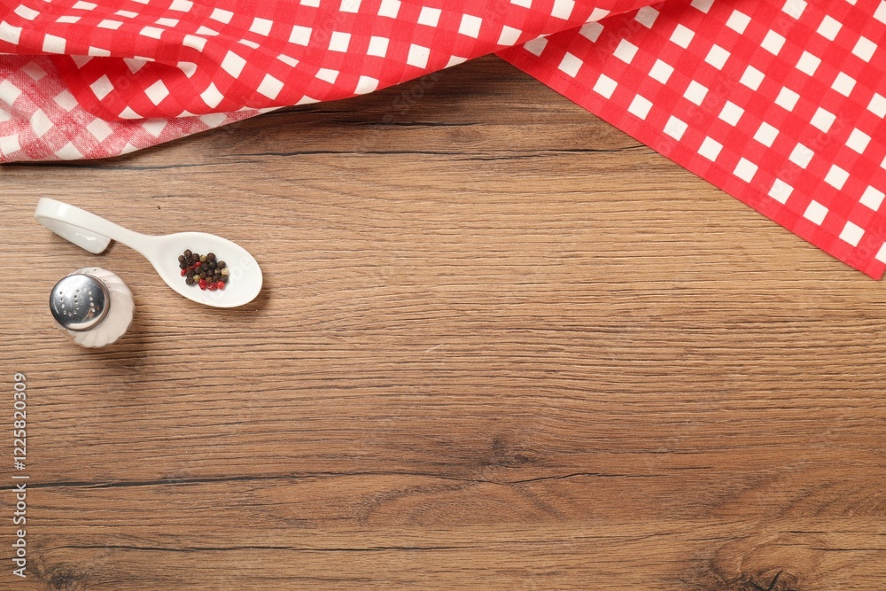 Obraz premium Checkered tablecloth and spices on wooden table, flat lay. Space for text