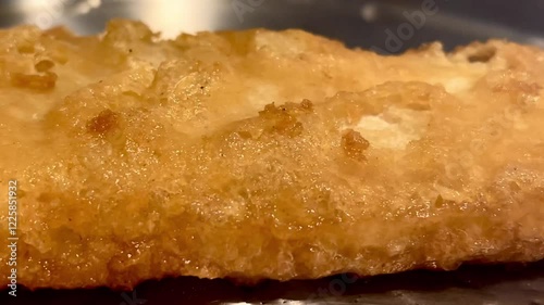 Crisp golden battered fish sizzling gently, embodying the essence of a traditional and comforting British dish, English fish and chips