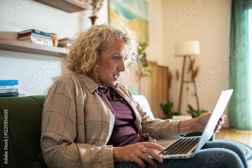 Shocked middle aged woman using laptop at home photo