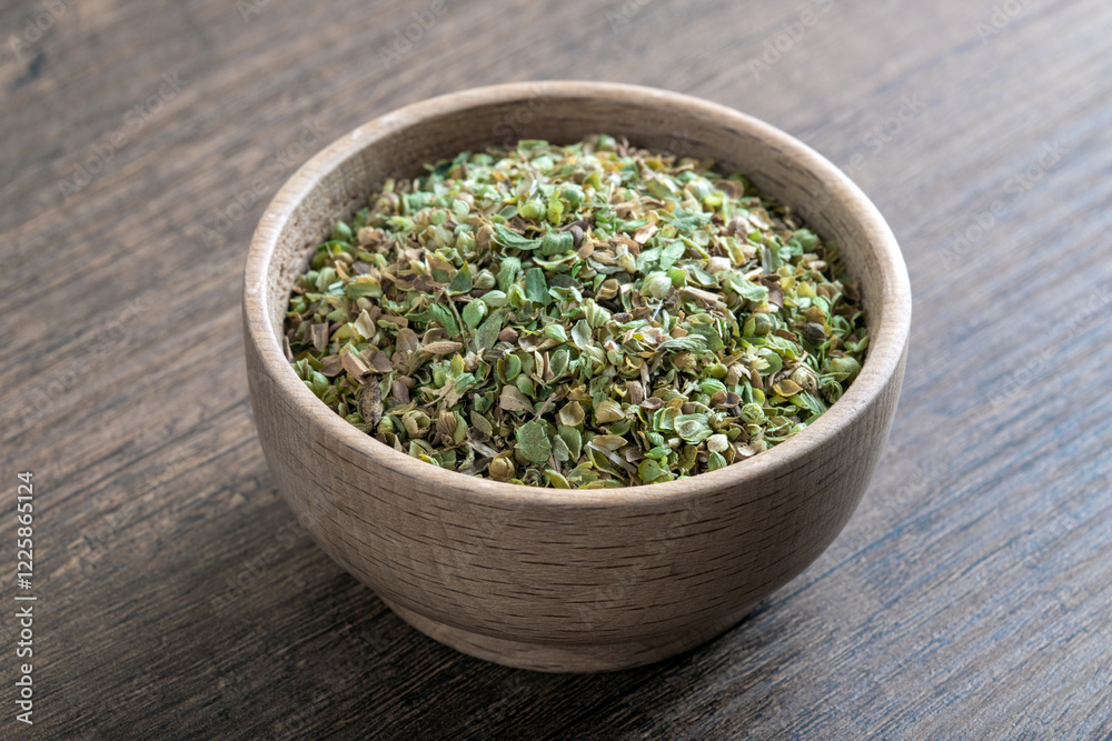 A bowl full of dried and ground organic mountain thyme on wooden table A bowl full of dried and ground organic mountain thyme on wooden table