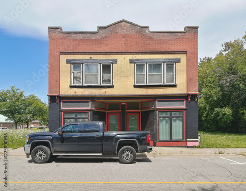A 4x4 jeep SUV van truck in front of a building made of bricks in a rural Canada area