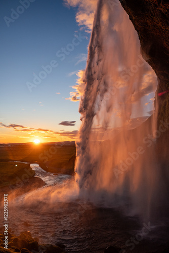 Majestic Seljalandsfoss Waterfall with amazing sunset illuminating the mist in a serene landscape area of Golden Circle in Iceland