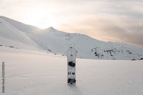 White splitboard stands in the snow against the background of a snowy plain and mountains with sharp peaks photo