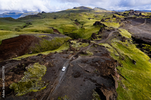 Aerial drone view exploring a valley landscape with a lone white car 4x4 on a dirt road to Thakgil (Pakgil) campsite near Vik in Iceland