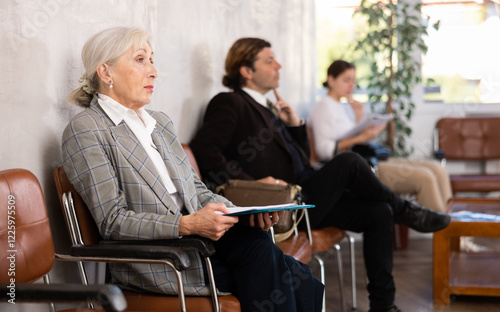 Foto Unemployed senior woman is waiting for job interview in waiting room