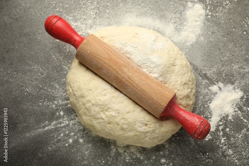 Fresh dough and rolling pin on grey table, top view
