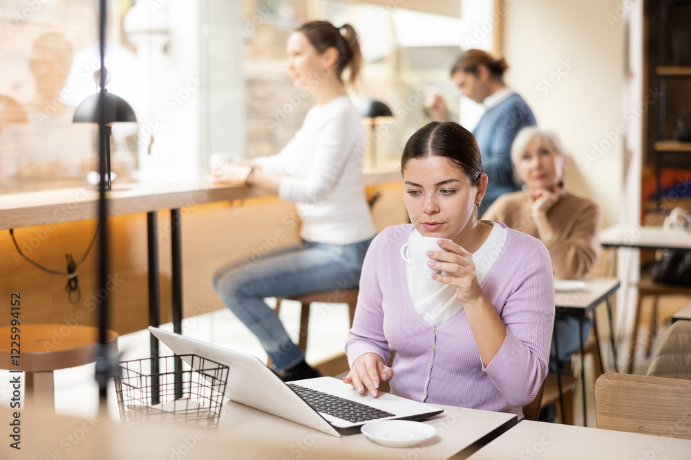 Young woman spending time in cozy coffeehouse with laptop and coffee Young woman spending time in cozy coffeehouse with laptop and coffee