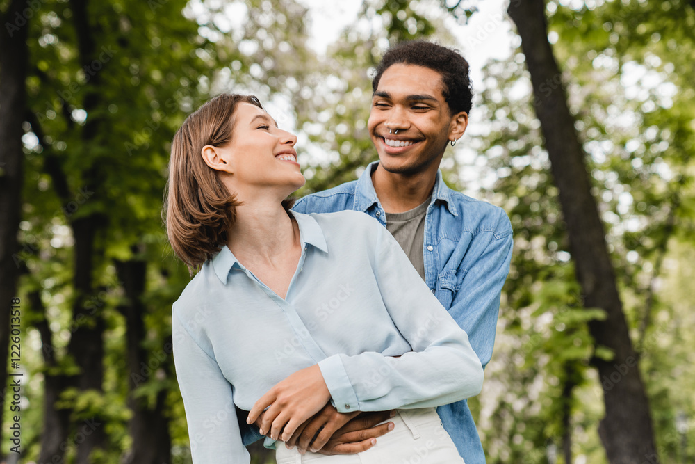 First true feelings. Young happy mixed-race couple students hugging embracing together in city park walking on romantic date. Love and relationship concept. Love at first sight. First true feelings. Young happy mixed-race couple students hugging embracing together in city park walking on romantic date. Love and relationship concept. Love at first sight.