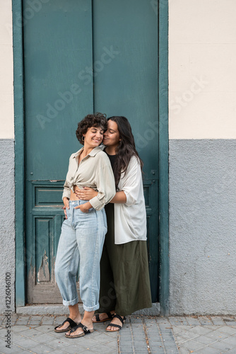 Loving lesbian couple embracing outdoors against green door photo