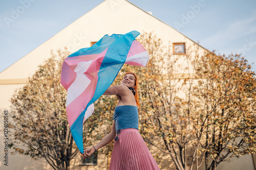 Young woman waving transgender pride flag in the city