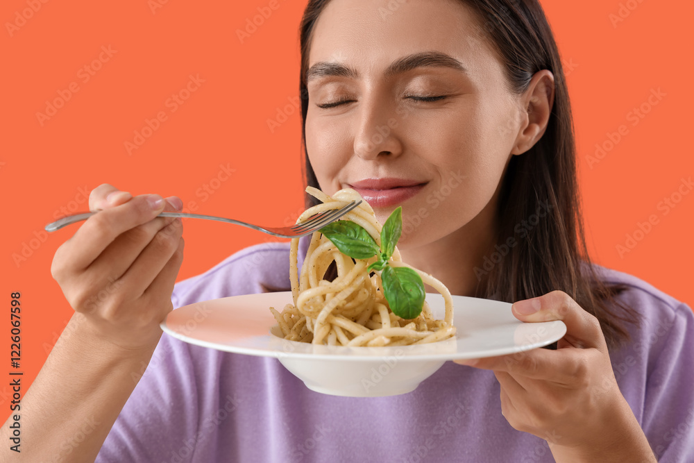 Young woman eating tasty pasta on orange background, closeup Young woman eating tasty pasta on orange background, closeup